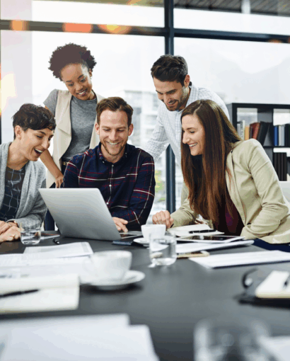 Groupe de personnes réunies autour d’un ordinateur portable dans une salle de réunion moderne, collaborant sur des documents et des projets professionnels.