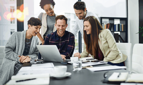 Groupe de personnes réunies autour d’un ordinateur portable dans une salle de réunion moderne, collaborant sur des documents et des projets professionnels.