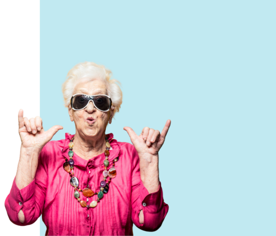 Personne portant une chemise rose vive et un collier coloré, levant les pouces vers elle, devant un fond bleu clair.